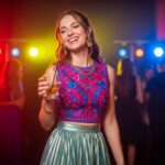 Młoda kobieta w modnym stroju na imprezie z rozmytymi kolorowymi światłami w tle